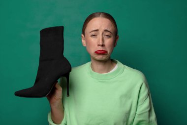 Genç sarışın kadın zarif bir çizme tutuyor.