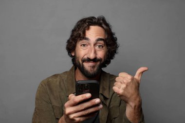 Genç sakallı adam akıllı telefon kullanıyor.