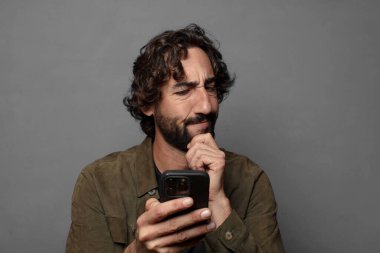 Genç sakallı adam akıllı telefon kullanıyor.