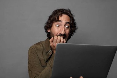 Genç sakallı adam dizüstü bilgisayar kullanıyor.