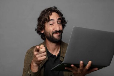 Genç sakallı adam dizüstü bilgisayar kullanıyor.