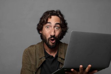 Genç sakallı adam dizüstü bilgisayar kullanıyor.