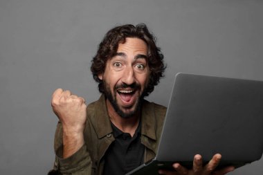 Genç sakallı adam dizüstü bilgisayar kullanıyor.