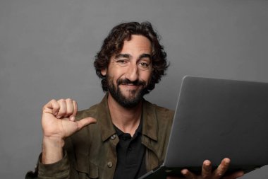Genç sakallı adam dizüstü bilgisayar kullanıyor.