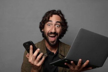 Genç sakallı adam dizüstü bilgisayar kullanıyor.