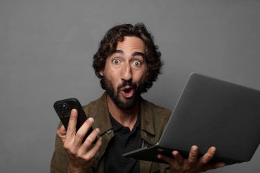 Genç sakallı adam dizüstü bilgisayar kullanıyor.