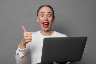 Neşeli bir şekilde gülümsüyor ve mutlu görünüyor, tasasız ve pozitif hissediyor.