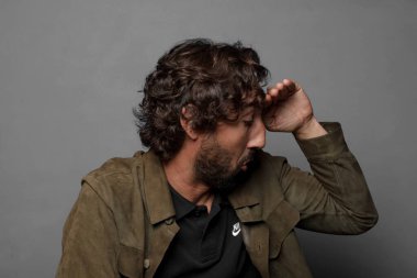 Afallamış ve şaşkın bir halde, el üstünde, uzaklara bakıyor, izliyor ya da arıyor.