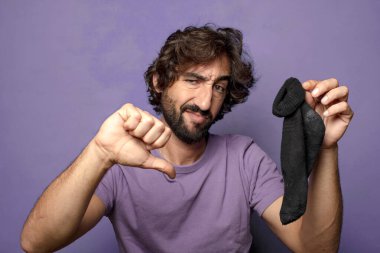 Kirli çorabı olan genç, sakallı bir adam.