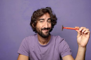 Traş makinesi olan genç, sakallı bir adam.