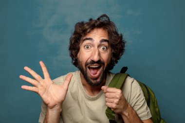 Çantası olan genç, sakallı bir adam.