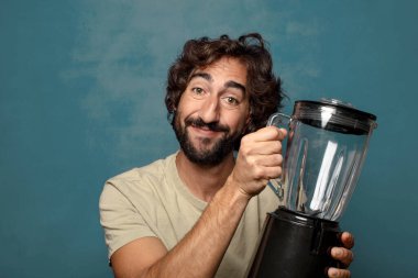Genç, sakallı, blender makineli bir adam.