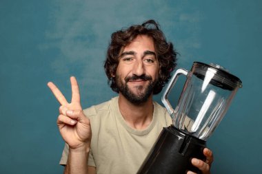 Genç, sakallı, blender makineli bir adam.