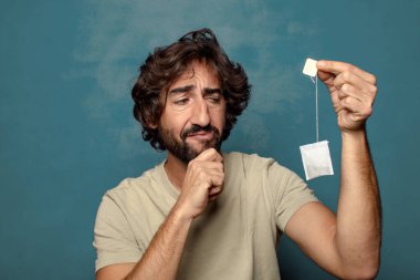 Genç, sakallı, çay içen bir adam.