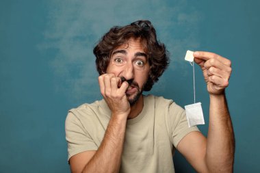 Genç, sakallı, çay içen bir adam.