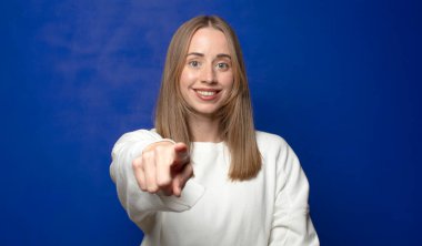 Tatmin olmuş, kendine güvenen, dost canlısı bir gülümsemeyle kameraya bakıp seni seçiyor.