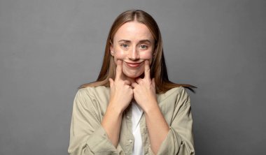 Kendi sahte gülüşüne güvenerek gülümsüyor.