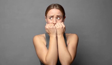 Endişeli, endişeli, stresli ve korkmuş görünüyor tırnaklarını yiyor ve yanal fotokopi için yer arıyor. fitness konsepti