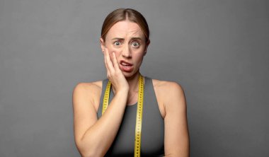 Şok ve inançsızlıkla ağzı açık, elleri yanakları ve kolları çaprazlanmış, sersemlemiş ve şaşırmış hissediyordu. fitness konsepti