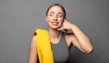 Neşeli bir şekilde gülümsüyor ve kamerayı işaret ediyor. Daha sonra seni arıyor, telefonla konuşuyor. fitness konsepti