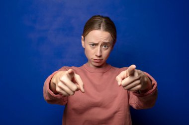 Sarışın kadın kamerayı iki parmağıyla ve kızgın bir ifadeyle sana görevini yapmanı söylüyor.