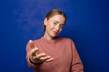 Sarışın kadın gülümsüyor, mutlu görünüyor, kendinden emin ve arkadaş canlısı, anlaşma yapmak için el sıkışma teklif ediyor, işbirliği yapıyor.