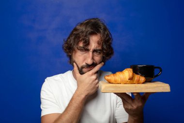 Genç, sakallı, Fransız kahvaltısı yapan bir adam.