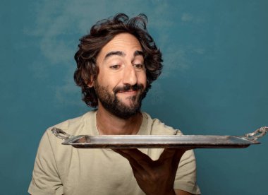 Gümüş tepsisi olan genç, sakallı bir adam.