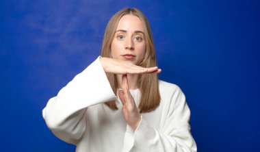 Ciddi görünüyor, sert, kızgın ve hoşnutsuz, mola işareti yapıyor.