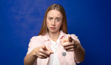 Kamerayı iki parmağınla ve kızgın bir ifadeyle sana görevini yapmanı söylüyor.