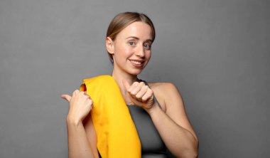 Neşeli bir şekilde gülümsüyor ve yan taraftaki fotokopi alanını işaret ediyor, mutlu ve tatmin olmuş hissediyordu. fitness konsepti