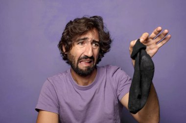 Kirli çorabı olan genç, sakallı bir adam.