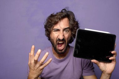 Genç, sakallı, dokunmatik ekranı tutan bir adam.