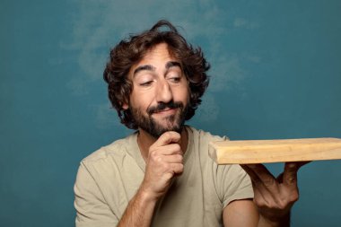 Boş tahta kesim masası olan genç, sakallı bir adam.