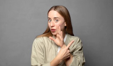 Şok olmuş bir ifade karşısında şaşırmış ve bir tarafı işaret ediyor.