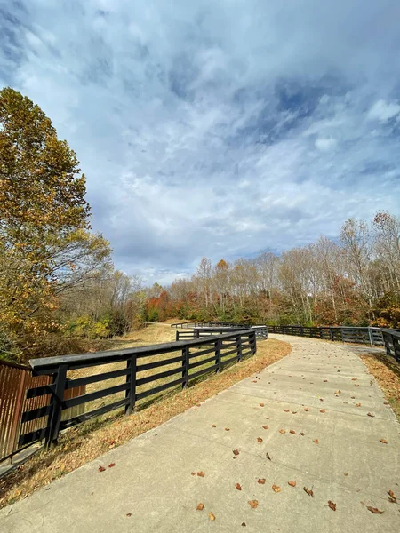 stock image Surrounded by fences, autumn leaves covered trail in a park