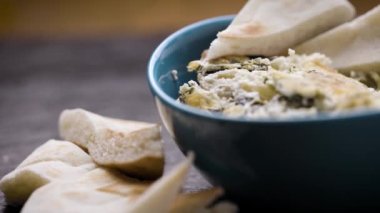 Bir kase ıspanaklı enginarı kapayın. Dilimlenmiş pide ekmeğiyle süsleyin.