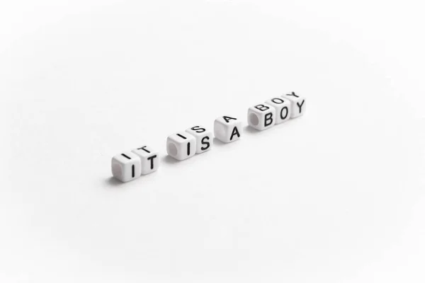 Gender reveal. It is a boy text on a perspective diagonally of the image. White plastic letter cubes placed on white background.