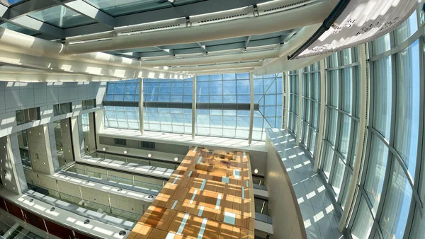 Entrance hallway of modern architecture office building during bright sunny day. Staircases and open corridors on different levels as visible from the ground level.