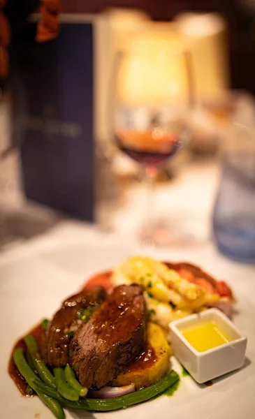Glamorous Surf and turf dish with boiled lobster and beef medallion on a table with glass of red wine