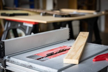 Marangozun atölyesi. Önünde testere ve üzerine tahta var.