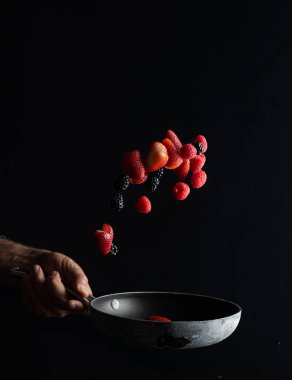 Aşçı, çilek, böğürtlen ve ahududu karışımını bir tavaya atarken, görsel efekt meyve bazlı bir tatlının hazırlanmasına benziyor..