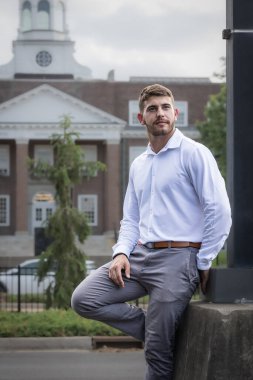 Sakallı ve beyaz gömlekli bir üniversite öğrencisi şehrin sokaklarında gözlerini kaçırıyor..