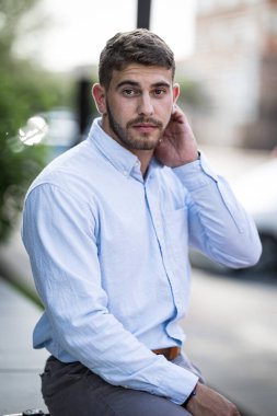 Şehirde dikilirken daracık görünen bir adamın portresi.