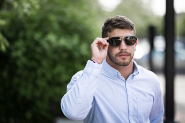 Dışarıda güneş gözlüğü takan genç yakışıklı adam. 