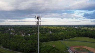 Lexington, Kentucky 'deki Gaziler Parkı' ndaki beyzbol sahalarının ön planda farklı antenleri olan 5G cep telefonu yineleyici kulesi.