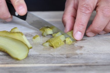 Adamın elleri yeşil salatalık kesiyor.