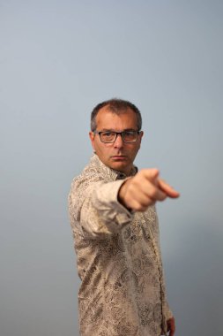 Gözlüklü ve gömlekli bir adam kameranın parmağını gösterir, parmaklarını gösterir..
