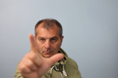 Orta yaşlı bir adamın portresi parmaklarıyla yarım kare şeklinde bir tabela yapıyor.