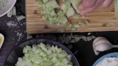 Aşçı, Bulgar Mlechna salatasıyla tabak hazırlamak için salatalık kesiyor